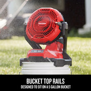 Photo of Craftsman red cordless fan CMCE003B sitting on a white 5-gallon bucket, spraying mist outdoors.