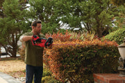 Photo of CRAFTSMAN hedge trimmer CMCHTS820D1, used outdoors, trimming bushes in a landscaped garden.